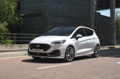 A white Ford Fiesta hatchback drives down a busy motorway.